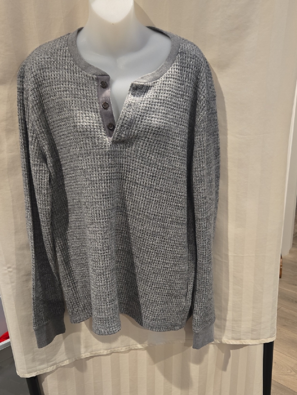 This is a textured grey waffle-knit thermal henley shirt featuring 3 Buttons